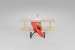 Toy biplane featuring a shiny yellow body, beige wings, large red spinning