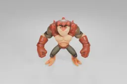 Muscular, cartoonish action figure with orange skin and lizard-like features