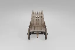 Wooden cart with four large spoked wheels and sturdy planks stands empty