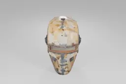 Rusty, weathered metal helmet with a narrow rectangular visor, scattered